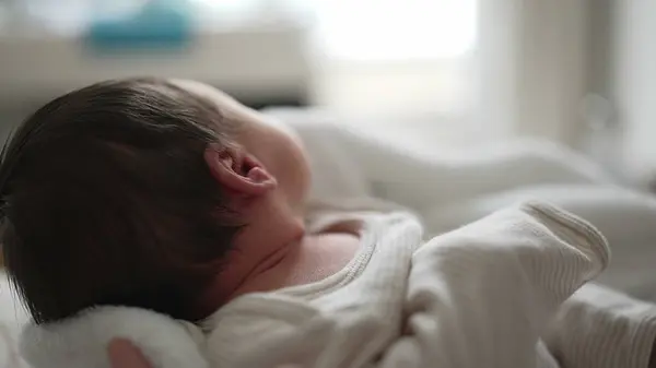 stock image Newborn baby looking up, mouth slightly open, wrapped in a soft blanket, cozy and safe in mothers arms, bright eyes, capturing the wonder and innocence of early life, peaceful atmosphere 