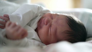 Yeni doğan bebek uyurken rahatsız hisseder, yüzünün kapanışı somurtkanlık gösterir, eski hayatın doğal ifadelerini yakalar, uyuyan bir bebeğin savunmasızlığını ve masumiyetini vurgular.