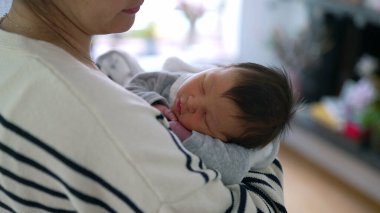 Bir annenin, yeni doğmuş bebeğini nazikçe kucağına alıp anne ve çocuk arasındaki derin sevgiyi, sıcaklığı ve şefkati yakalaması.