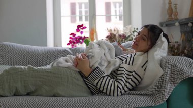 Anne yeni doğmuş bebeğini kucaklayarak rahat bir kanepeye uzanır huzurlu bir yuva ortamında sükuneti kucaklar. Anne ve çocuk arasındaki barışçıl bağ