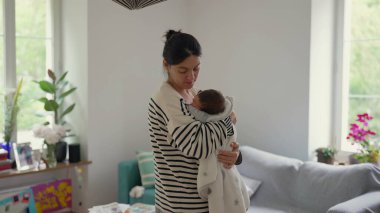 Anne, yeni doğmuş bebeğini nazikçe bir battaniyeye sarıp, anne ve çocuk arasındaki bağın ve sıcaklığın sessiz ve samimi anını yakalıyor.