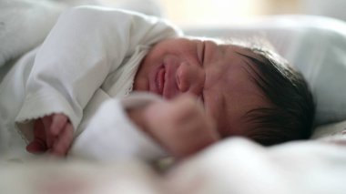 Yeni doğan bebek uyurken rahatsız hisseder, yüzünün kapanışı somurtkanlık gösterir, eski hayatın doğal ifadelerini yakalar, uyuyan bir bebeğin savunmasızlığını ve masumiyetini vurgular.