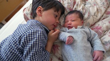 Ağabeyi, yeni doğan kardeşiyle yan yana yatar ve iki kardeş arasındaki sevgi ve sevgiyi vurgulayan yakın ve samimi bir yakınlaşma anını paylaşır.