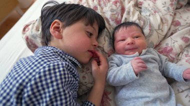 Ağabeyi, yeni doğan kardeşiyle yan yana yatar ve iki kardeş arasındaki sevgi ve sevgiyi vurgulayan yakın ve samimi bir yakınlaşma anını paylaşır.