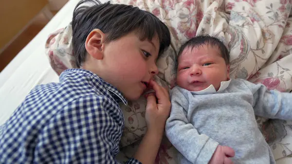 Ağabeyi, yeni doğan kardeşiyle yan yana yatar ve iki kardeş arasındaki sevgi ve sevgiyi vurgulayan yakın ve samimi bir yakınlaşma anını paylaşır.