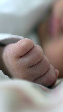 Yumuşak ve sıcak bir atmosferle çevrili hassas yüz detaylarına odaklanan, derin uykuda yeni doğmuş bir bebeğin huzur, sükunet ve konforu nazik bir ortamda uyandıran huzurlu bir görüntüsü.