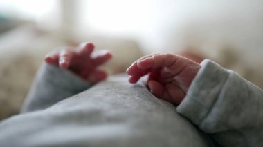 Yeni doğan bebeğin ellerinin yavaşça karnının üzerinde dinlenmesi, bebekliğin narin ve hassas doğasını, huzurlu ve sakin bir ortamda sergilemektedir.