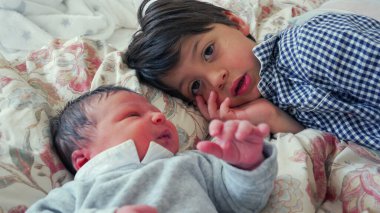 Older brother gazing at newborn sibling with curiosity and affection, creating a moment of deep connection and bonding in a cozy home environment, full of warmth and tenderness clipart