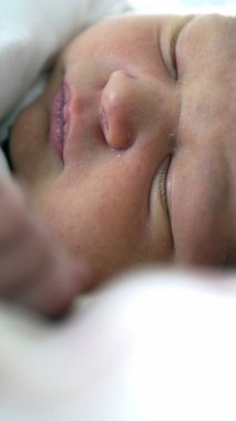 Yumuşak ve sıcak bir atmosferle çevrili hassas yüz detaylarına odaklanan, derin uykuda yeni doğmuş bir bebeğin huzur, sükunet ve konforu nazik bir ortamda uyandıran huzurlu bir görüntüsü.