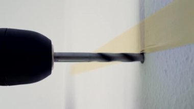 Duvarda delik açan bir matkabın yakın çekimi, bir inşaat veya ev geliştirme sürecini gösteriyor, sondaj işleminin eylemini ve içerdiği hassasiyeti vurguluyor
