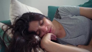 Kanepede uzanan, eli çenesinin altında huzurlu bir şekilde uyuyan, rahat ve ev ortamında rahat bir kadının yakın çekimi.
