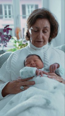 Büyükannesi uyuyan yeni doğan torununu kucaklıyor, huzurlu ve rahatlatıcı bir dinlenme anı yakalıyor ve sakin bir ev ortamında iletişim kuruyor.