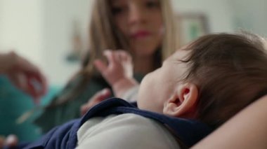 Kucağında büyük bir çocuğun nazikçe uzanıp bebeğe dokunduğu ve kardeşler arasındaki hassas bağı yakaladığı bir bebeğin yakın çekimi.