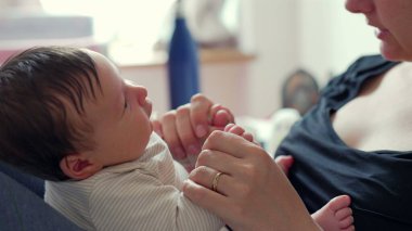 Annenin yeni doğmuş bebeğini kucağına alıp, onların ellerine ve aralarındaki bağlara odaklandığı, yumuşak, rahat bir ortamda sevgi ve şefkat gösterdiği yakın plan.