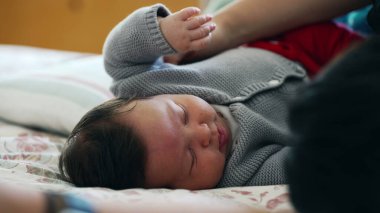 Bebek rahat bir yatakta huzurlu bir şekilde uyuyor, sıcak bir kazak giyiyor, güvenli ve sevgi dolu bir evde huzur ve sükuneti somutlaştırıyor, huzurlu bir huzur sergiliyor.