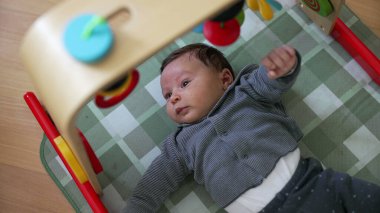 Bebek aktivite minderinde oynuyor, renkli oyuncaklarla etkileşime giriyor. Neşeli ortam, bebeğin merak ve erken gelişim ortamını ön plana çıkarıyor.