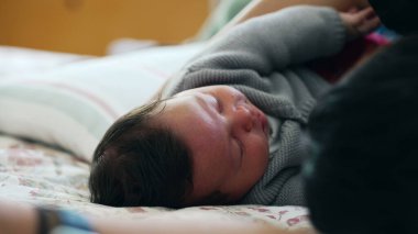 Bebek rahat bir yatakta huzurlu bir şekilde uyuyor, sıcak bir kazak giyiyor, güvenli ve sevgi dolu bir evde huzur ve sükuneti somutlaştırıyor, huzurlu bir huzur sergiliyor.