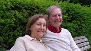 Yaşlı bir çift bankta oturuyor, kameraya gülümsüyor, bir park ortamında yemyeşil ile çevrili, uzun süreli ilişkilerinin sıcaklığını ve sevgisini sergiliyorlar.