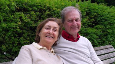 Yaşlı bir çift bankta oturuyor, kameraya gülümsüyor, bir park ortamında yemyeşil ile çevrili, uzun süreli ilişkilerinin sıcaklığını ve sevgisini sergiliyorlar.