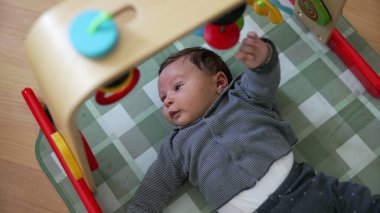 Bebek aktivite minderinde oynuyor, renkli oyuncaklarla etkileşime giriyor. Neşeli ortam, bebeğin merak ve erken gelişim ortamını ön plana çıkarıyor.