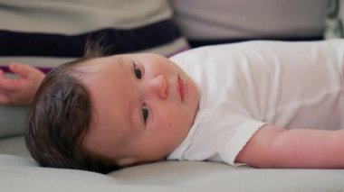 Bebeğin kanepeye uzanmış rahat ve rahat bir ev ortamında rahatlarken dikkatli bir şekilde bakması.