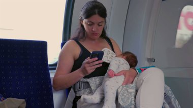 Anne kucağında bebekle birden fazla iş yapıyor, tren yolculuğu sırasında telefona dalmış, modern ebeveynlik, çocuk bakımı ve dijital ilişki arasındaki dengeyi sağlıyor.