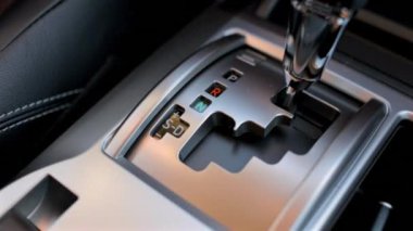Otomatik viteste geçişi vurgulayarak, park halindeki pozisyondan sürüş moduna doğru hareket eden bir araba vites kolunun yakın plan görüntüsü. Aracın içindeki pürüzsüz harekete odaklanın..