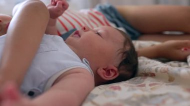 Bebeğin yatağın üzerine uzanmış, daha büyük bir çocuğun eli bebeğin kafasında yavaşça dinleniyor. Kardeş bağını ve iç mekanda barışçıl bir etkileşimi yakalamak
