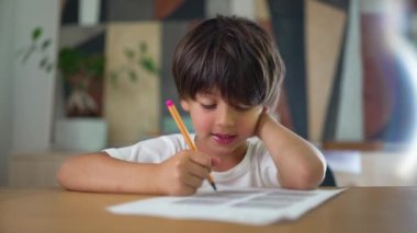 Odaklanma ve konsantrasyonla bir çizim üzerinde çalışan, ev ortamında bir masada oturan, yaratıcılık, öğrenme ve çocukluk gelişimi gösteren genç bir çocuk.