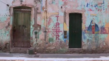 Çocuk Salvador 'un tarihi bir caddesinde yıpranmış, grafiti kaplı bir duvarın önünden geçiyor. Yaşlanmış mimari ve canlı sanatın arasında kentsel yaşamın dinamik enerjisi