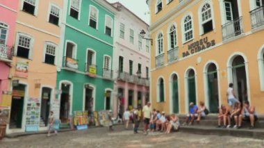 Pelourinho, Salvador 'daki renkli koloni binaları. Taş basamaklarda oturan insanlar, tarihi merkezde güneşli bir günün tadını çıkarıyorlar, canlı mimari ile çevrili.