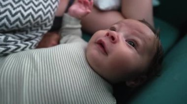 Bebek kanepede şakacı bir ifadeyle yatıyor, dili dışarı çıkıyor ve neşeli görünüyor, rahat bir çevreyle çevrili, neşeli ve neşeli bir an sergiliyor.