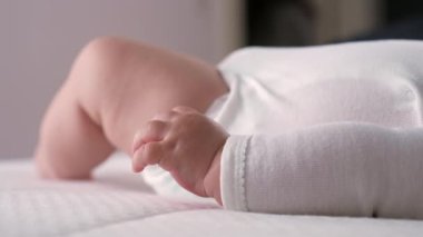 Bebeklerin ellerinin yatakta dinlendiği yakın plan çekimler, erken çocukluğun ince ve narin ayrıntılarını gözler önüne seriyor. Yumuşak ışık, sakin ve rahatlatıcı bir ortamda hassasiyeti ve kırılganlığı vurgular.