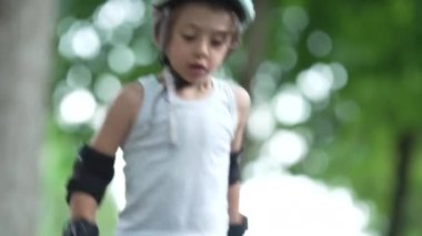 Genç çocuk kaykayı yere yerleştiriyor, yolculuk için hazırlanıyor. Etkin bir şekilde itmeden önce iki eliyle ayarlamak için eğiliyor, odaklanma ve kontrol gösteriyor.