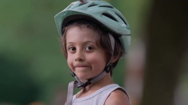 Kask takan genç bir çocuğun yakın plan portresi, kurnaz bir gülümsemeyle kameraya bakıyor. İfadesi, bir açık hava macerasının özünü, özgüvenini ve hazırlığını yansıtıyor.