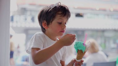 Genç bir çocuk renkli bir dondurma külahının tadını çıkarıyor. Parlak ve neşeli bir ortamda bir kaşık dolusu yemek yerken konsantre oluyor. Bir çocuğun hayatındaki basit zevklerin neşeli anı. 