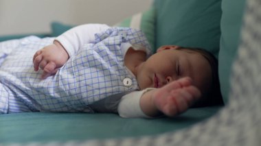 Kanepede uyuyan bir bebeğin, huzurlu ve huzurlu bir anı yakaladığı yakın plan. Samimi ortam ve yumuşak ışıklandırma bebeğin sükunetini ve masumiyetini vurguluyor.