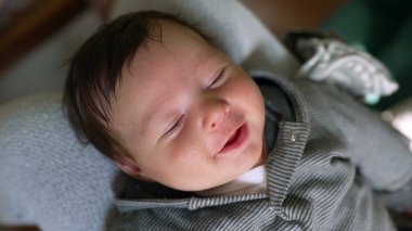 Yumuşak bir yüzeyde uzanmış neşeli bir bebeğin yakın çekimi. Rahat duruş ve parlak ifade bebeğin memnuniyetini ve anın sıcaklığını vurgular.