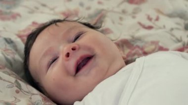 Bebek çiçek tarhında dinleniyor, dikkatlice yukarıya bakıyor sakin ve meraklı bir ifadeyle. Bebek nazik tavrı huzurlu ve huzurlu bir atmosfer yaratıyor. Aile anları için mükemmel..