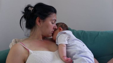 Anne ve bebek kanepede sessiz ve samimi bir anı paylaşırlar. Sarılmaları, huzurlu bir yuvada derin bir bağ ve sıcaklığı yansıtır.