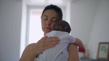 Anne, bebeğini nazikçe kapalı bir şekilde kucağına alıyor. Huzurlu ve besleyici bir ortamda derin bir sevgi ve bağ kuruyor.
