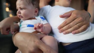 Bir restoranda kucağında bebek ve küçük bir çocuk olan anne kucağında, her iki çocuk da onun üzerinde dinleniyor, birden fazla iş yapan anne ve babasıyla samimi bir aile anı ve iki çocuğa da bakımı sağlıyor.