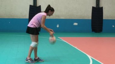 Kapalı alanda görev yapan voleybol oyuncusu, maç sırasında topa odaklanarak ve kararlılıkla vuruyor, rekabetin ortasında sahada atletizm ve yetenek gösteriyor.