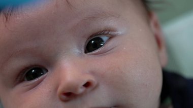 Bir bebeğin yüzüne ve gözlerine aşırı yakın çekim, merakla yukarıya bakıyor. Yeni doğmuş bir bebeğin çevreyi gözlerken detaylı görüntüsü.