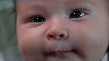 Bir bebeğin yüzüne ve gözlerine aşırı yakın çekim, merakla yukarıya bakıyor. Yeni doğmuş bir bebeğin çevreyi gözlerken detaylı görüntüsü.