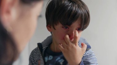 Anne, oğlu gözleri yaşlı, üzgün ve duygusal bir şekilde dinlerken konuşuyor. Anne, destekleyici bir ev ortamında rahatlık ve rehberlik sunar.