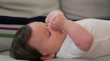 Bebeğin kanepeye uzanmış rahat ve rahat bir ev ortamında rahatlarken dikkatli bir şekilde bakması.