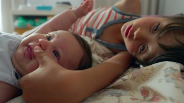 Çocuk bir bebekle yatakta uzanıyor. Uzağa bakarken kollarını bebeğin üzerine uzatıyor. Kardeşler arasındaki bağın altını çizerek sessiz bir an.