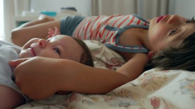 Çocuk bir bebekle yatakta uzanıyor. Uzağa bakarken kollarını bebeğin üzerine uzatıyor. Kardeşler arasındaki bağın altını çizerek sessiz bir an.