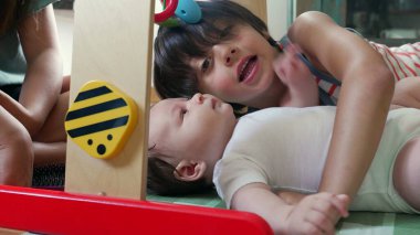 Young boy lying next to a baby on the floor, showing affection and bonding as he gently interacts with the baby during playtime in a home environment clipart